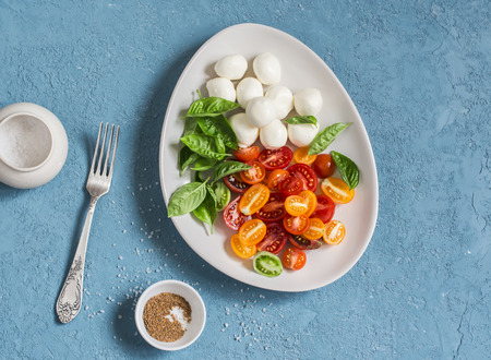 Caprese salad. Fresh salad with tomatoes, mozzarella and basil.  On a blue background.の写真素材