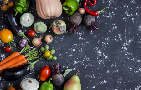 Autumn vegetable harvest. Pumpkin, eggplant, peppers, carrots, tomatoes, onions, garlic, beets on a dark background, top view. Free space for textの写真素材