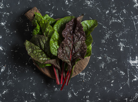 Fresh swiss chard or mangold  on a wooden cutting board on a dark backgroundの写真素材