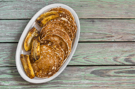 Pancake with honey and fried bananas on a ceramic plate on a dark wooden background. Delicious breakfast or snackの写真素材