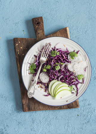 Red cabbage and apple slaw. Tasty vegetarian diet food. On a blue background, top viewの写真素材