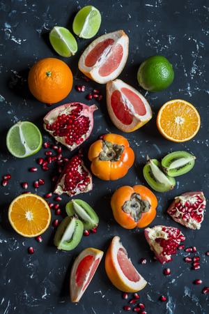 Variation of fresh fruit - grapefruit, persimmon, kiwi, pomegranate, orange, lime. On the tena background, top viewの写真素材