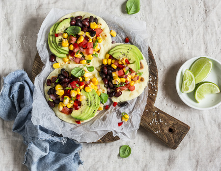 Spicy bean tostadas with corn salsa and avocado  on a light background, top view. Delicious vegetarian lunch or snackの写真素材