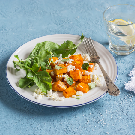 Baked pumpkin and goat cheese salad on a blue background. Healthy foodの写真素材