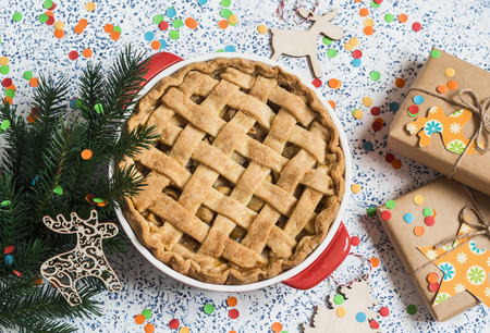 Apple pie, christmas gifts and decorations on light background, top view