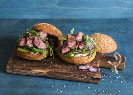 Homemade steak burger on wooden cutting board on a blue backgroundの写真素材