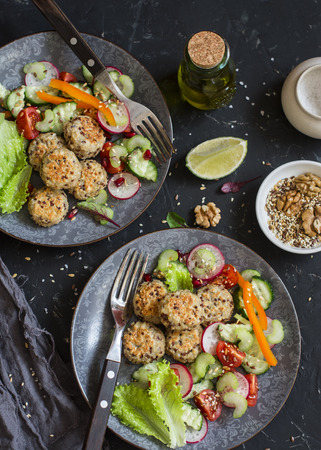 Vegetarian lunch - quinoa meatballs and vegetable salad on a dark table, top viewの写真素材