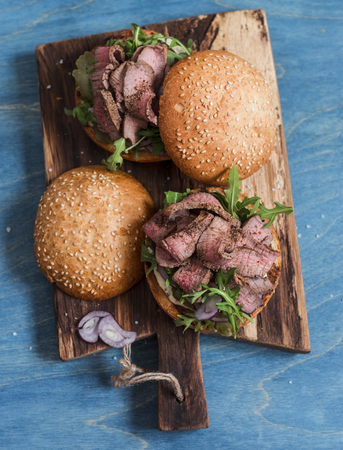 Homemade steak burger on wooden cutting board on a blue backgroundの写真素材