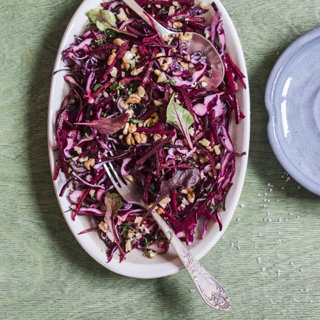 Red cabbage, beetroot and walnuts salad. Healthy vegetarian detox food. On wooden background, top viewの写真素材
