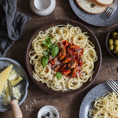 Mediterranean style lunch. Spaghetti with canned mussels and tomato sauce. On a wooden table, top view. Flat layの写真素材