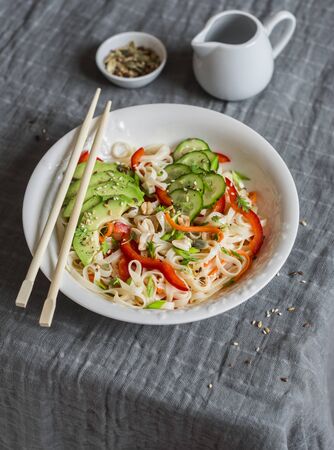 Udon noodles with quick pickled vegetables and avocado on a gray table. Healthy vegetarian food conceptの写真素材