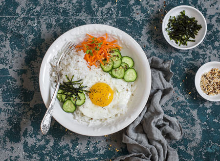 Rice with fried egg, pickled carrots, cucumber and seaweed. Healthy diet food concept. Top viewの写真素材