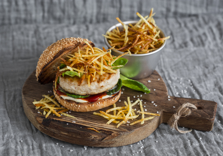Grilled chicken and fries burger on wooden cutting boardの写真素材