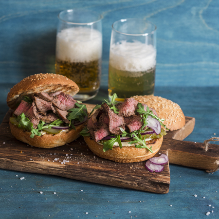 Homemade steak beef burgers and two glasses beers on a wooden tableの写真素材