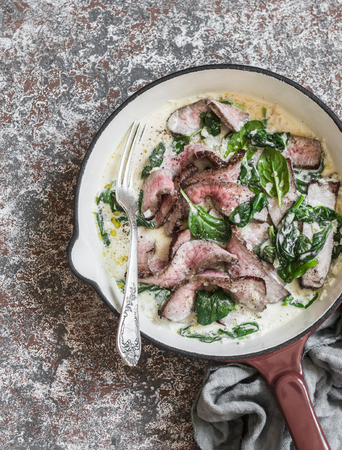 Beef steak and a creamy spinach sauce in a cast iron skillet, top view. Delicious healthy lunchの写真素材