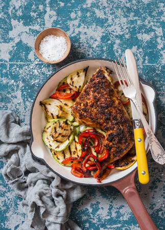 BBQ chicken and grilled vegetables in a cast iron skillet on a dark background, top view. Delicious healthy foodの写真素材
