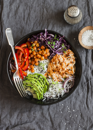 Grilled chicken, rice, spicy chickpeas, avocado mash, cabbage, pepper buddha bowl on dark background, top view. Delicious balanced food conceptの写真素材