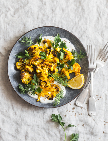 Roasted turmeric cauliflower with greek yogurt dressing. Delicious healthy food on a grey background, top viewの写真素材