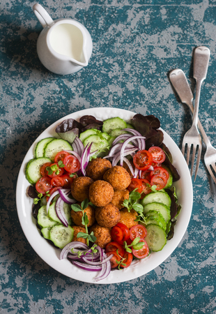 Falafel and vegetables salad bowl. Delicious vegetarian food concept. Buddha bowl on dark background, top viewの写真素材