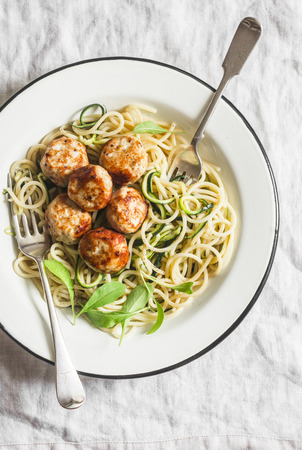 Spaghetti with cheesy chicken meatballs and zucchini noodles. Delicious lunch on a light background, top viewの写真素材
