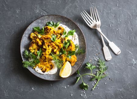 Roasted turmeric cauliflower with greek yogurt dressing. Delicious healthy snack on a dark background, top viewの写真素材