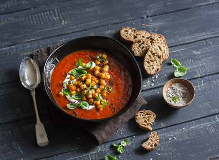 Tomato soup with spicy fried chickpeas on a dark wooden table, top view. Vegetarian food conceptの写真素材