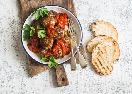 Baked meatballs with tomato sauce and herbs on a wooden cutting Board on white background. Top view. Delicious lunchの写真素材