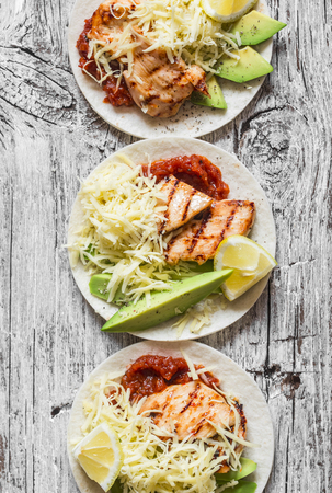 Grilled chicken, avocado, cheese and spicy tomato sauce tortillas on wooden rustic background, top viewの写真素材