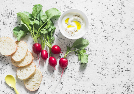Fresh garden radishes, greek yogurt and baguette - healthy meal on a light background, top viewの写真素材