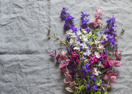 Wild flowers bouquet on gray linen background, top view. Vintage style. Free space for textの写真素材