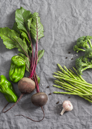 Fresh vegetables - beets, asparagus, broccoli, pepper, garlic on a gray background, top view. Free space, flat layの写真素材