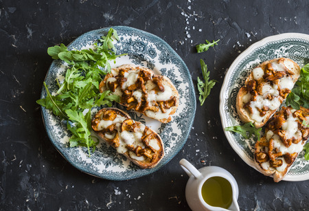 Mushrooms  tartine. Baked sandwiches with mushrooms chanterelles and mozzarella on a dark background, top viewの写真素材