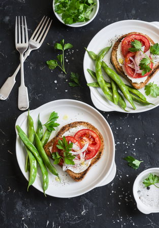 Tomato and cheese sandwiches and green beans is a healthy vegetarian breakfast or snack on a dark table, top view. Flat layの写真素材