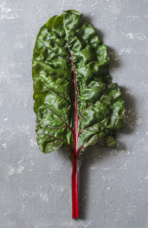 Fresh leaf of swiss chard on a gray background, top view. Free space for text