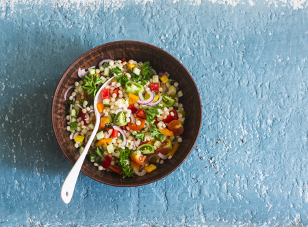 Israeli cous cous ptitim vegetables tabbouleh salad on a blue background, top view. Vegetarian food conceptの写真素材