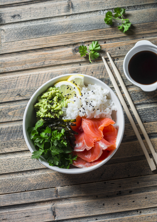 Smoked salmon sushi bowl on wooden table, top view. Rice, avocado puree, salmon - healthy food conceptの写真素材
