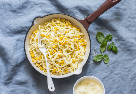Creamy corn pasta in a cast iron skillet on a blue background, top viewの写真素材