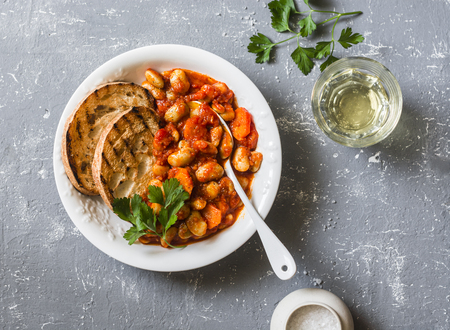 Spicy braised lima beans in tomato sauce and ciabatta toast on a grey background, top view. Delicious vegetarian lunch vegetable proteinの写真素材