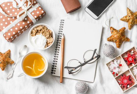 Morning breakfast christmas inspiration planning concept. Yoghurt with whole grain cereal and tea with lemon, christmas decorations, blank note pad on a light background, top view. Flat layの写真素材