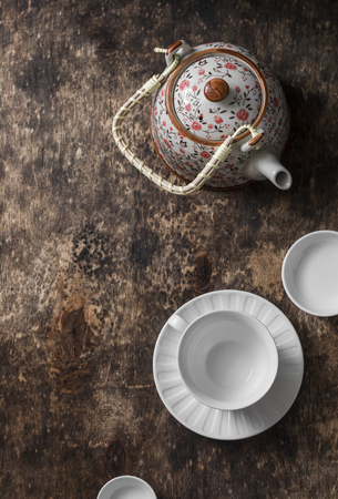 Tea set on a wooden table, top view. Teapot, empty white tea cup on a brown background, top view. Free space for textの写真素材