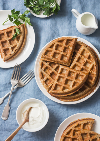 Whole wheat savory breakfast viennese waffles, cream and milk on blue background, top viewの写真素材