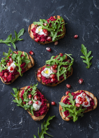 Arugula, beet hummus grilled sandwiches on dark background, top view. Delicious healthy appetizer or snack. Flat layの写真素材