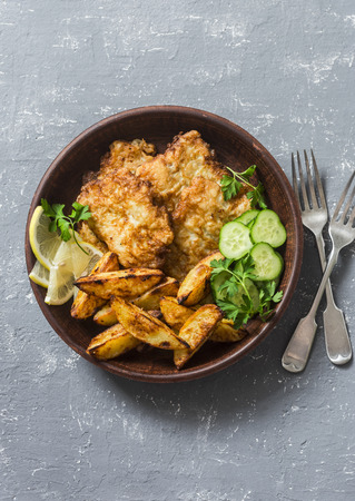 Fried fish and garlic baked potatoes on a grey background, top view. Fish and chips. Appetizers or snacksの写真素材
