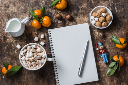 Christmas wooden background with hot chocolate, clean notebook, tangerines, christmas decorations. Free space for text, top view, flat layの写真素材