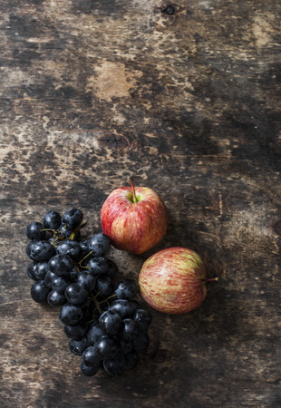 Fresh ripe autumn fruit apples and grapes on rustic wooden background, top view. Free space for textの写真素材