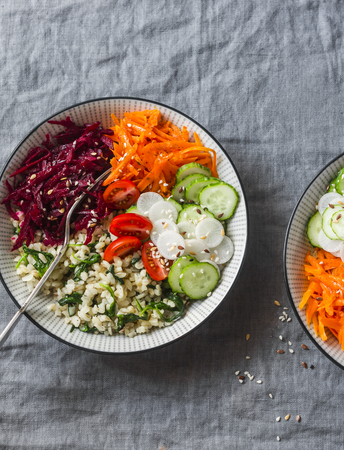 Bulgur, spinach, beets, carrots, cucumbers, tomatoes, daikon - balanced healthy food lunch. On a grey background, top view. Comfort autumn winter vegetarian foodの写真素材