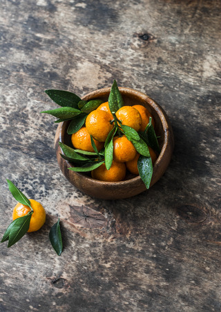 Fresh ripe tangerines in a wooden bowl on wooden background. Free spaceの写真素材