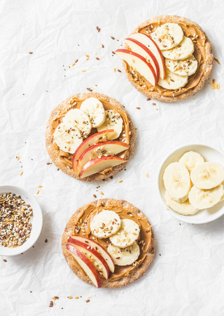 Peanut butter, apple, banana, flax and chia seed  crackers toast on a light background, top viewの写真素材
