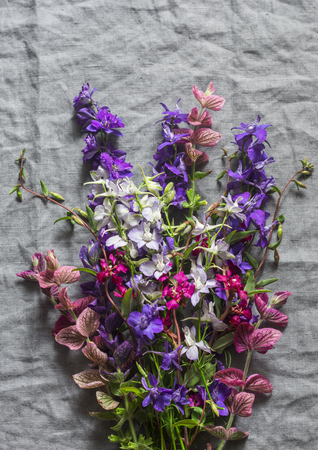 Wild garden flowers bouquet on gray linen background, top view. Free space for textの写真素材