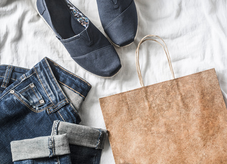 Women's clothing buy concept. Jeans, sneakers, paper bag on a light background, top viewの写真素材